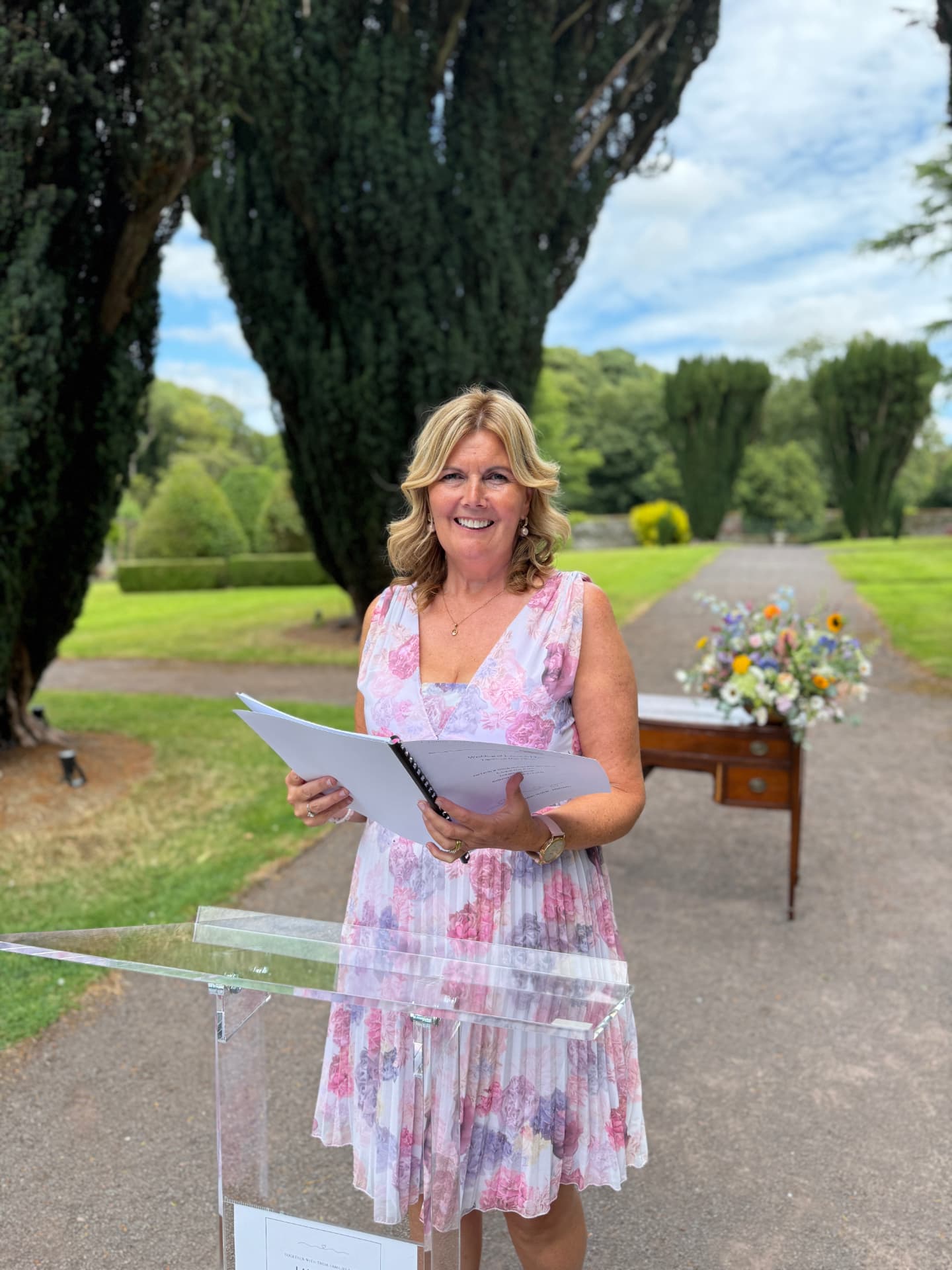 Grá, wedding celebrant, holding a ceremony script in a country house garden