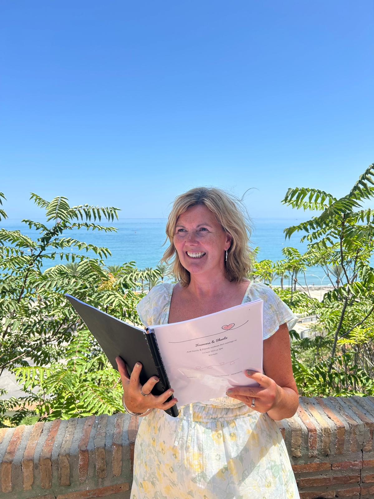Grá holding a personalised ceremony script overlooking the sea
